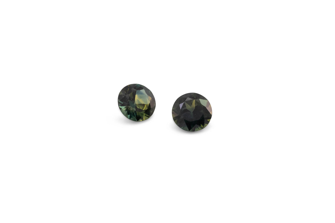 A pair of radiant cut blue/green Australian sapphire gemstones are displayed on a white background.