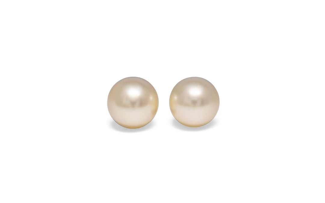 A pair of semi round, pink, white south sea pearls are displayed on a white background.