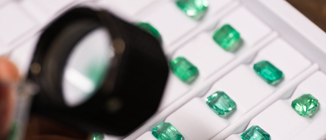 A selection of Colombian emeralds are being inspected with a jewellers loupe