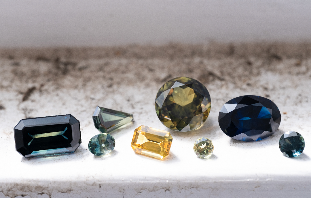 A selection of Australian sapphires in various cuts and colours is displayed on a windowsill.