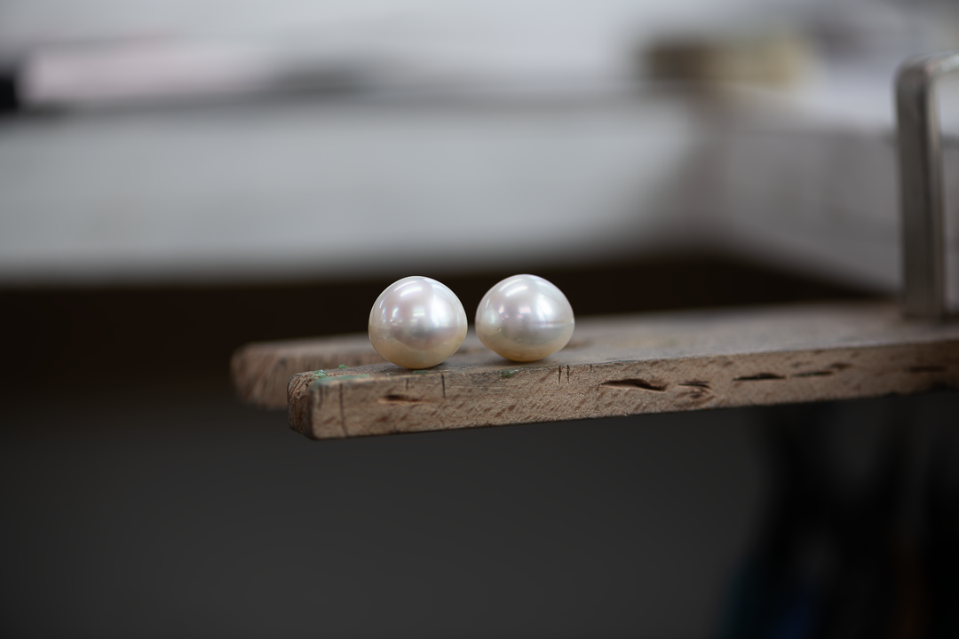 A pair of round golden South Sea pearls are displayed on a white background.