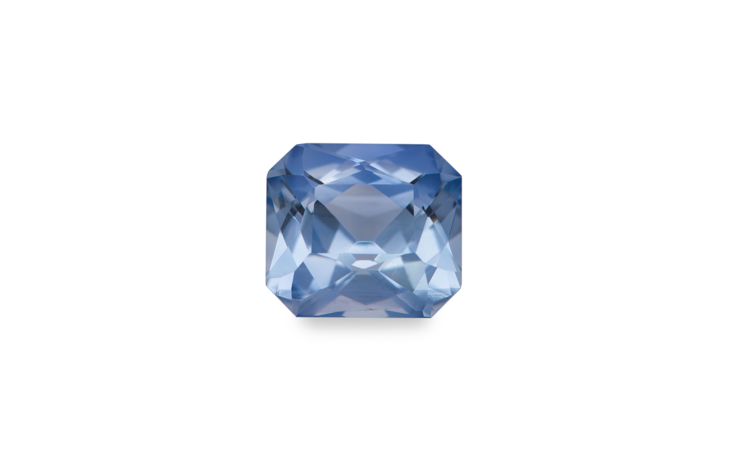 A cushion cut cornflower blue Ceylon sapphire gemstone is displayed on a white background.