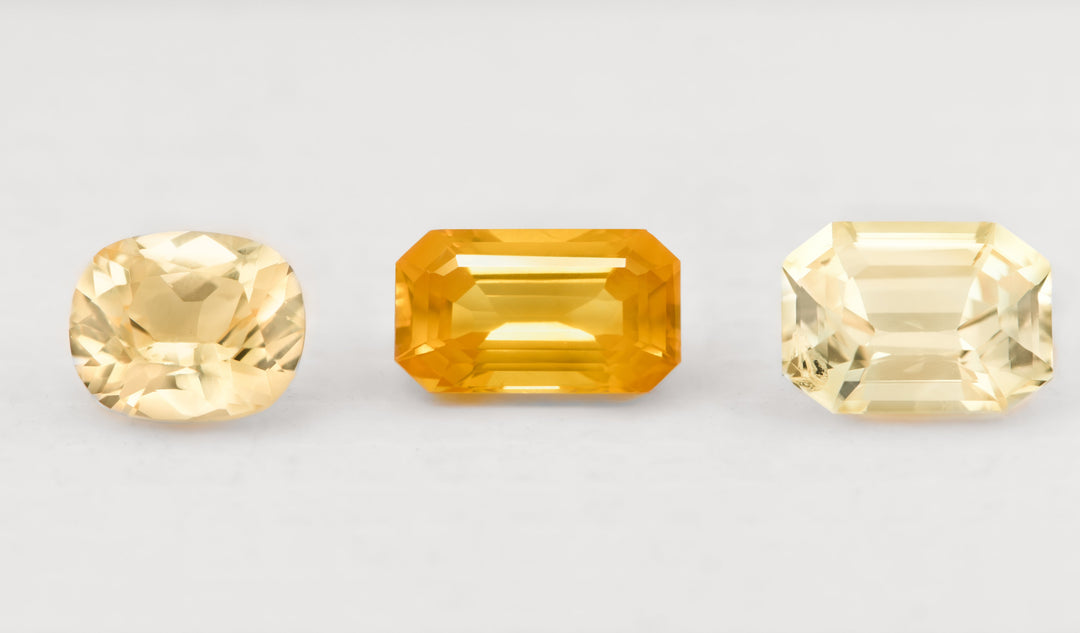 A selection of oval and cushion cut yellow sapphires sit in a white background. 