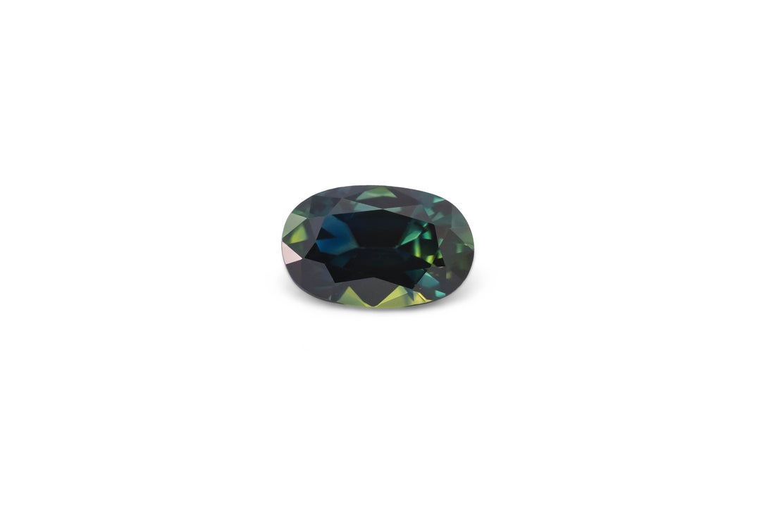 An oval cut Australian parti sapphire gemstone is displayed on a white background.
