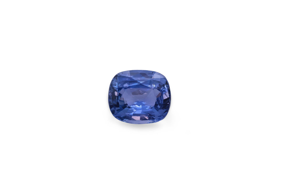 A cushion cut cornflower blue Ceylon sapphire gemstone is displayed on a white background.