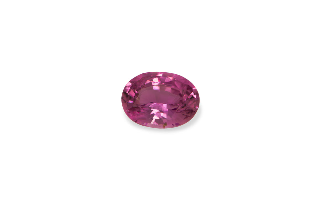 A oval cut pink Ceylon sapphire gemstone is displayed on a white background.