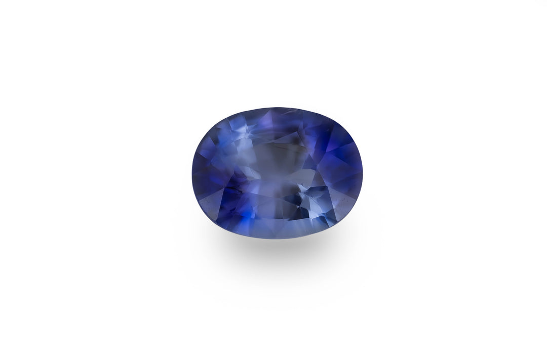 A cushion cut blue Ceylon sapphire gemstone is displayed on a white background.
