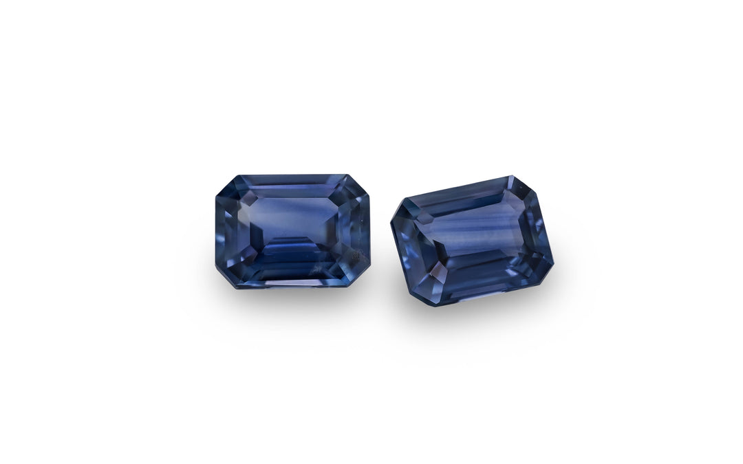 A pair of blue emerald cut Australian sapphire gemstones is displayed on a white background.