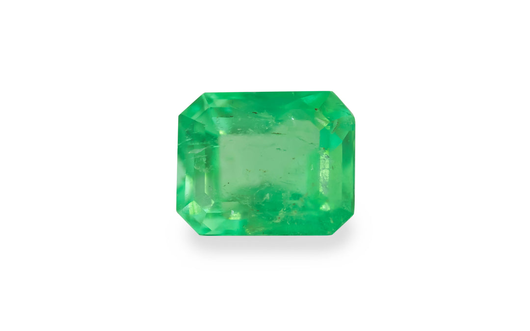 An emerald cut green Colombian emerald gemstone is displayed on a white background