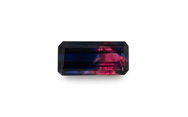  An emerald cut vibrant pink and deep purple blue Winza sapphire gemstone is displayed on a white background.