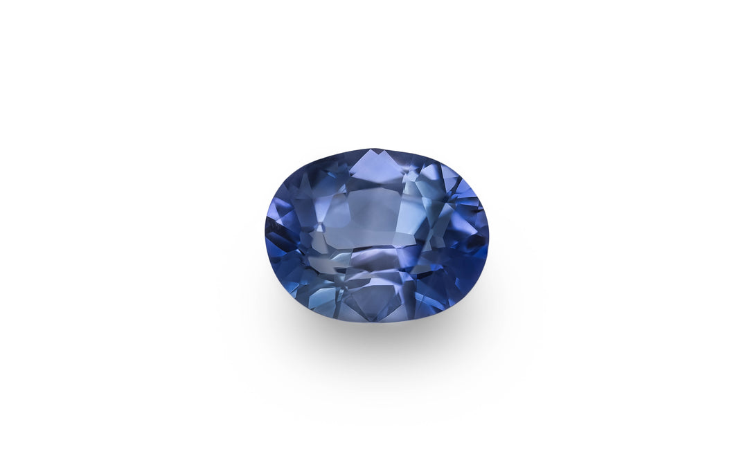 A oval cut blue Ceylon sapphire gemstone is displayed on a white background.