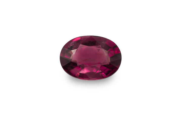An oval cut magenta pink tourmaline gemstone is displayed on a white background.