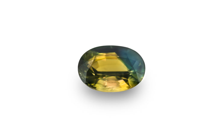An oval cut, bright yellow, deep blue and green Australian parti sapphire gemstone is displayed on a white background.