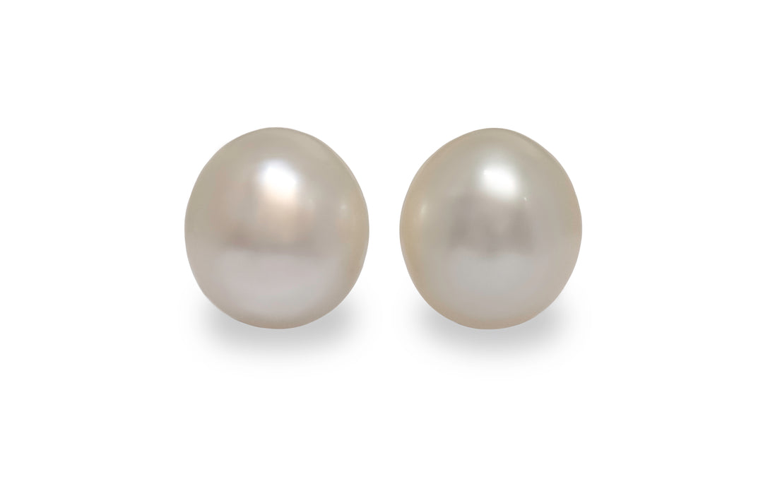 A pair of oval white south sea pearls are displayed on a white background.
