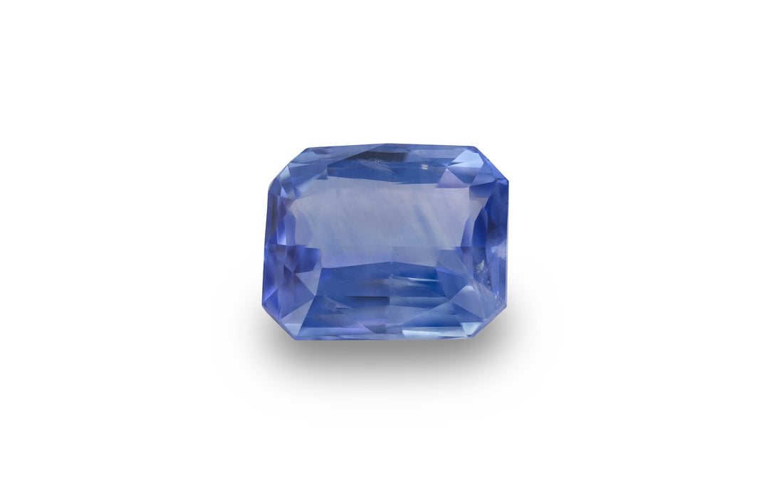 A radiant cut blue Ceylon sapphire gemstone is displayed on a white background.