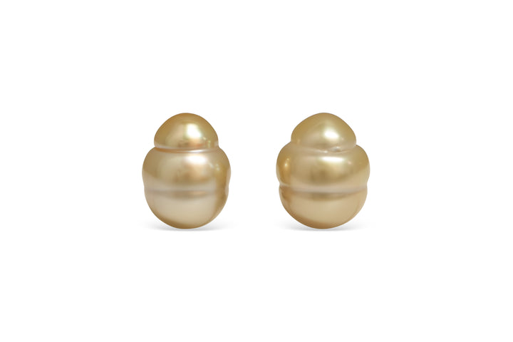 A baroque shape deep Golden South Sea pearl pair is displayed on a white background.