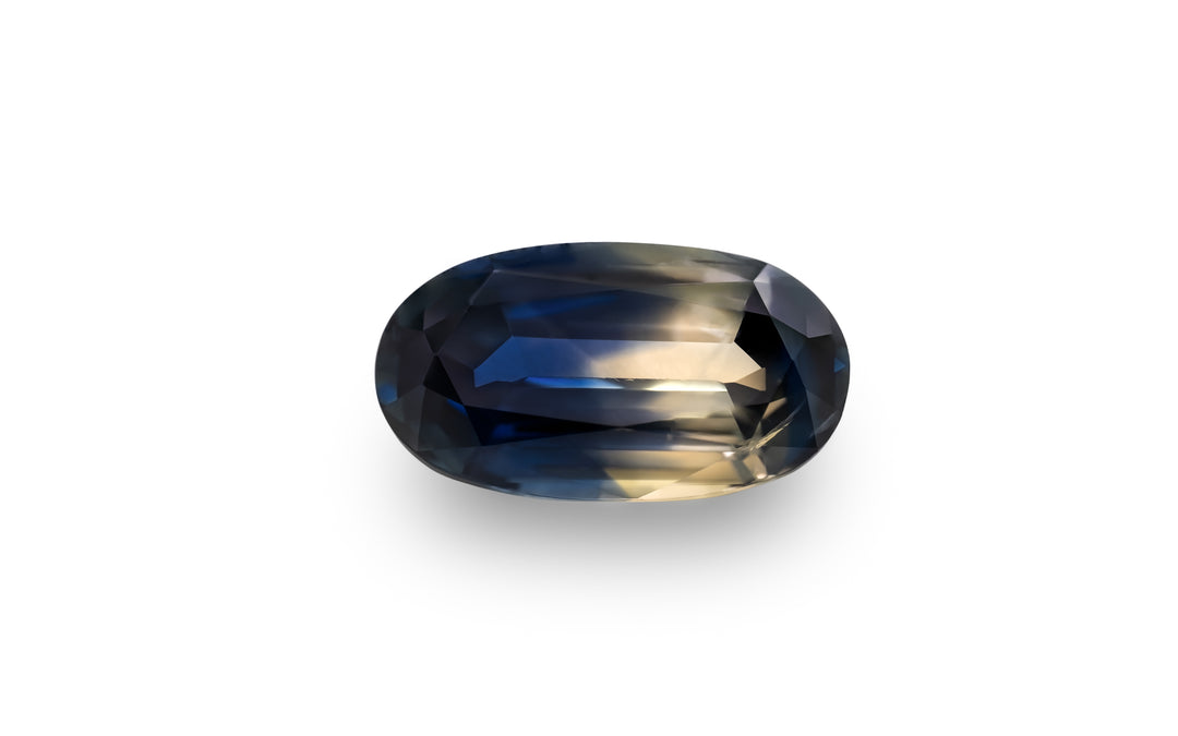 A cushion cut soft muted yellow and royal blue Australian Parti sapphire is displayed on a white background.