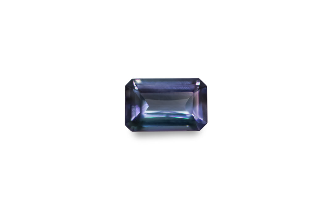 An emerald cut bi colour purple, blue, green Tanzanite is displayed on a white background.