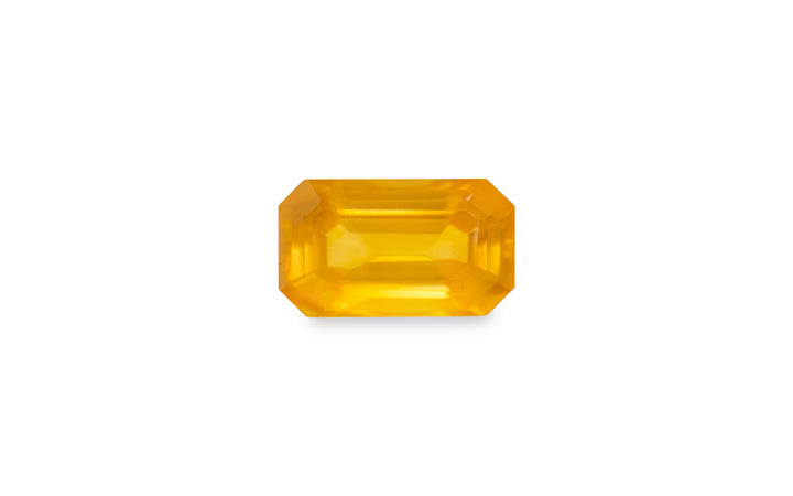 An emerald cut golden yellow sapphire gemstone is displayed on a white background.