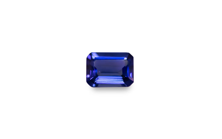 An emerald cut purple blue Tanzanite gemstone is displayed on a white background. 