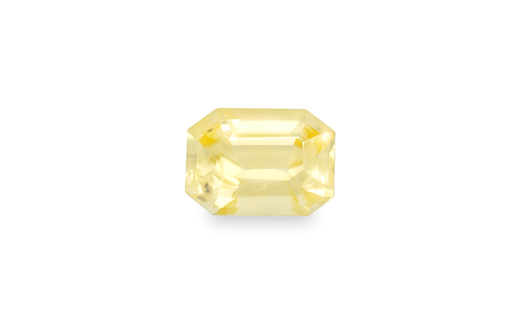 An emerald cut yellow sapphire gemstone is displayed on a white background.