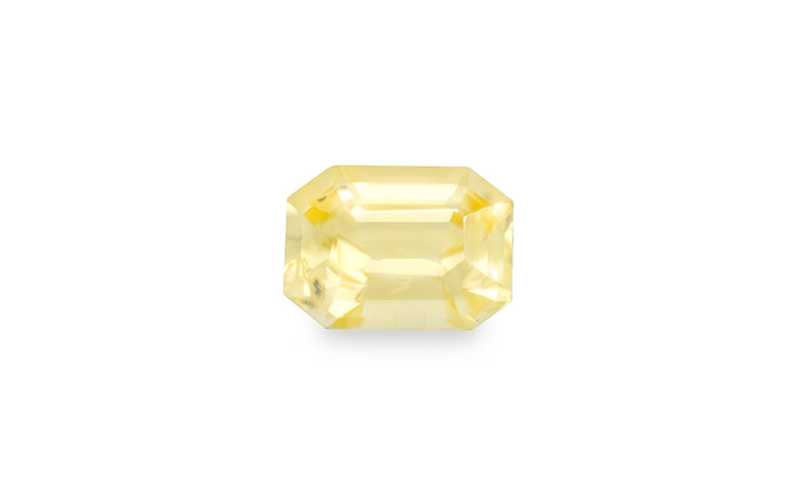 An emerald cut yellow sapphire gemstone is displayed on a white background.