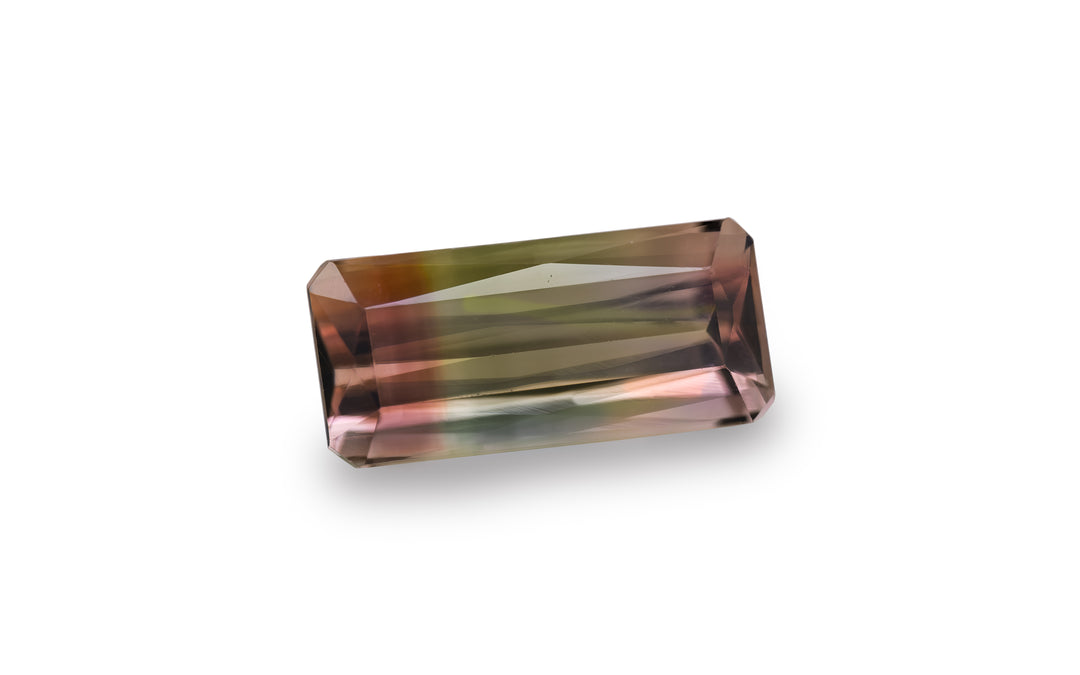 An emerald scissor cut bi-colour pink and green tourmaline gemstone is displayed on a white background.