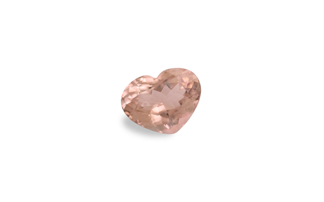 An heart cut peach morganite gemstone is displayed on a white background.