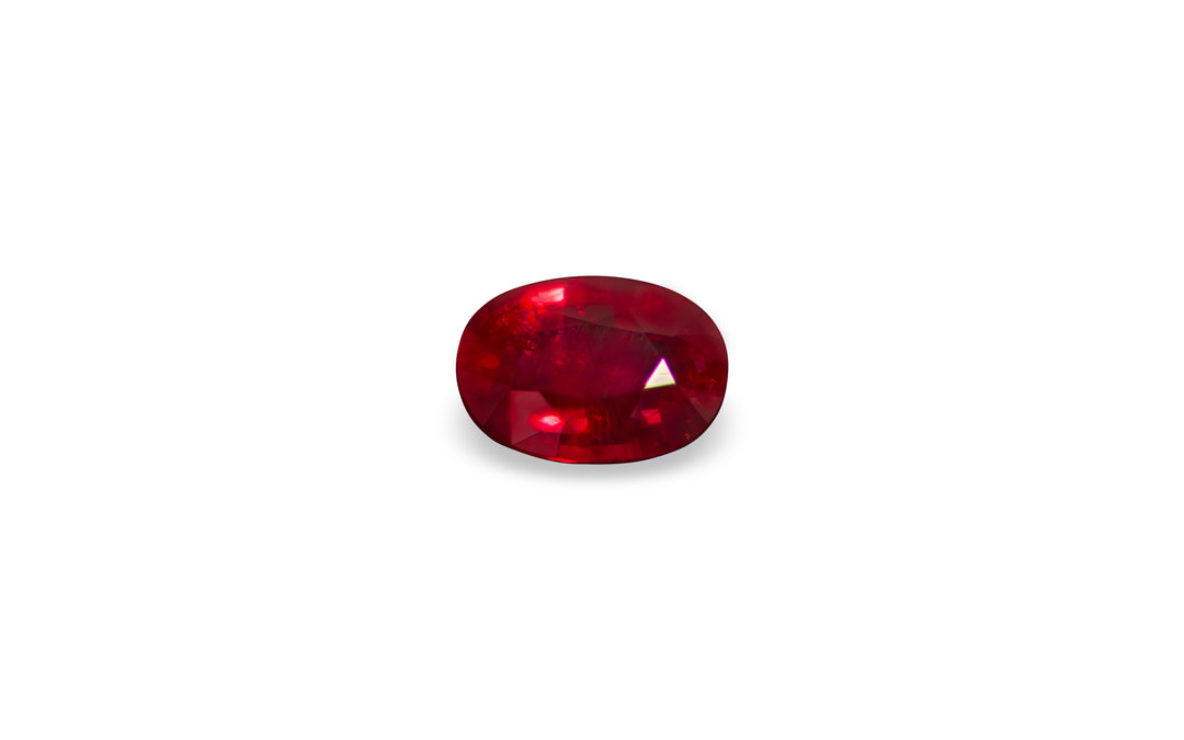 An oval cut Burmese ruby gemstone is displayed on a white background.