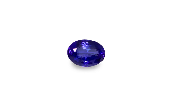 An oval cut intense blue Tanzanite is displayed on a white background.