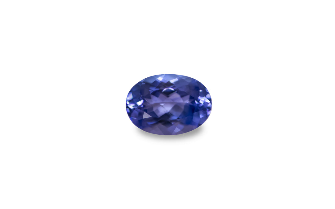 An oval cut purple blue Tanzanite gemstone is displayed on a white background.