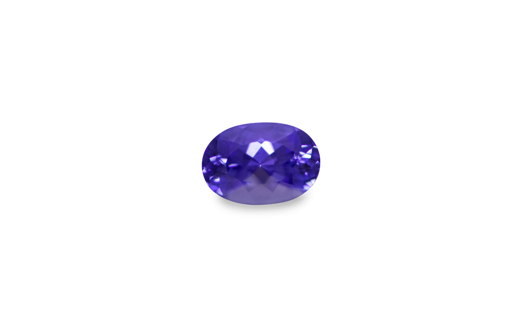 An oval cut purple blue Tanzanite gemstone is displayed on a white background.