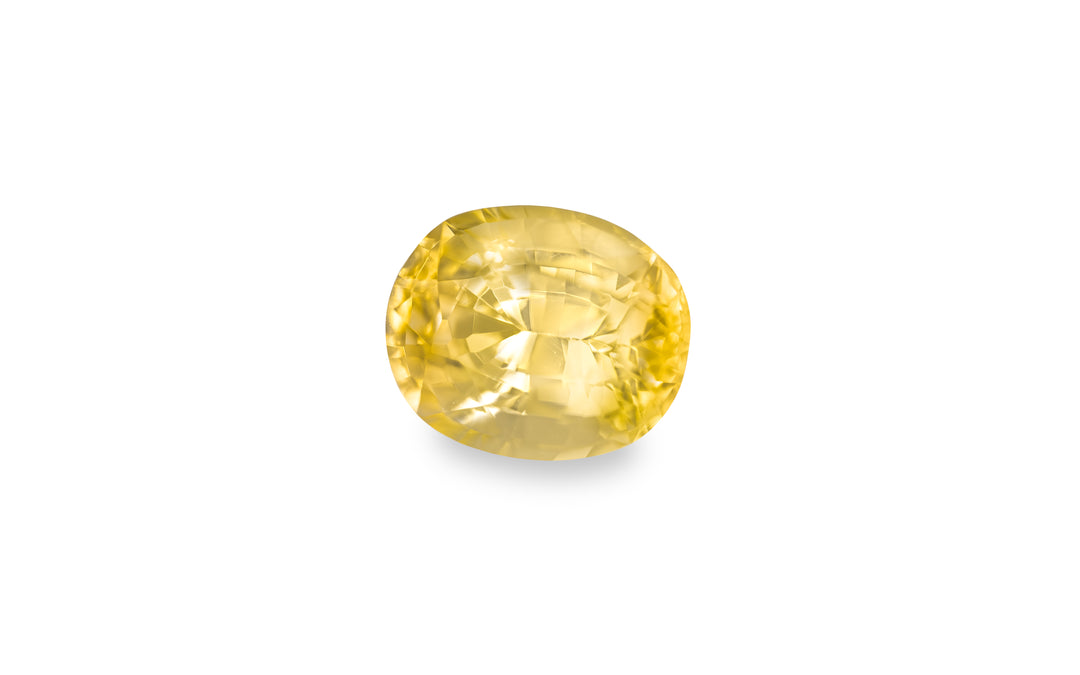 An oval cut yellow sapphire gemstone is displayed on a white background.