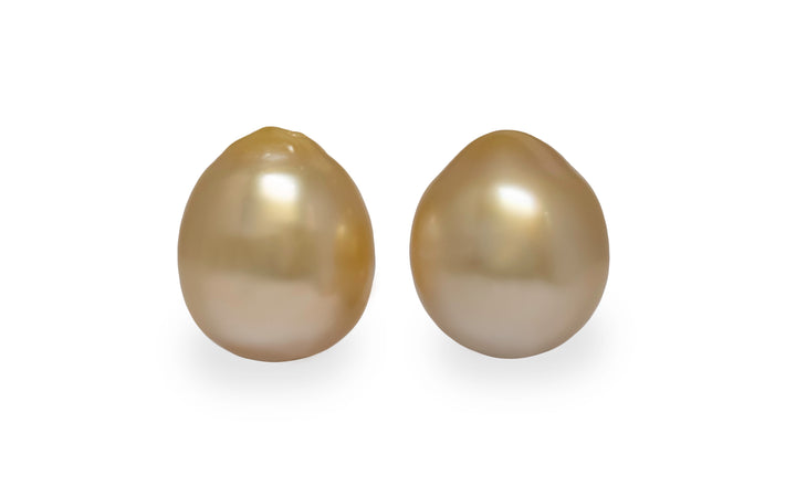 A pair of oval golden south sea pearls are displayed on a white background.