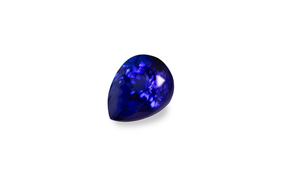 A pear cut intense blue tanzanite gemstone is displayed on a white background. 
