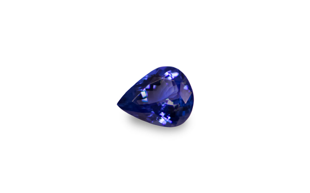 A pear cut intense purple blue Tanzanite is displayed on a white background.