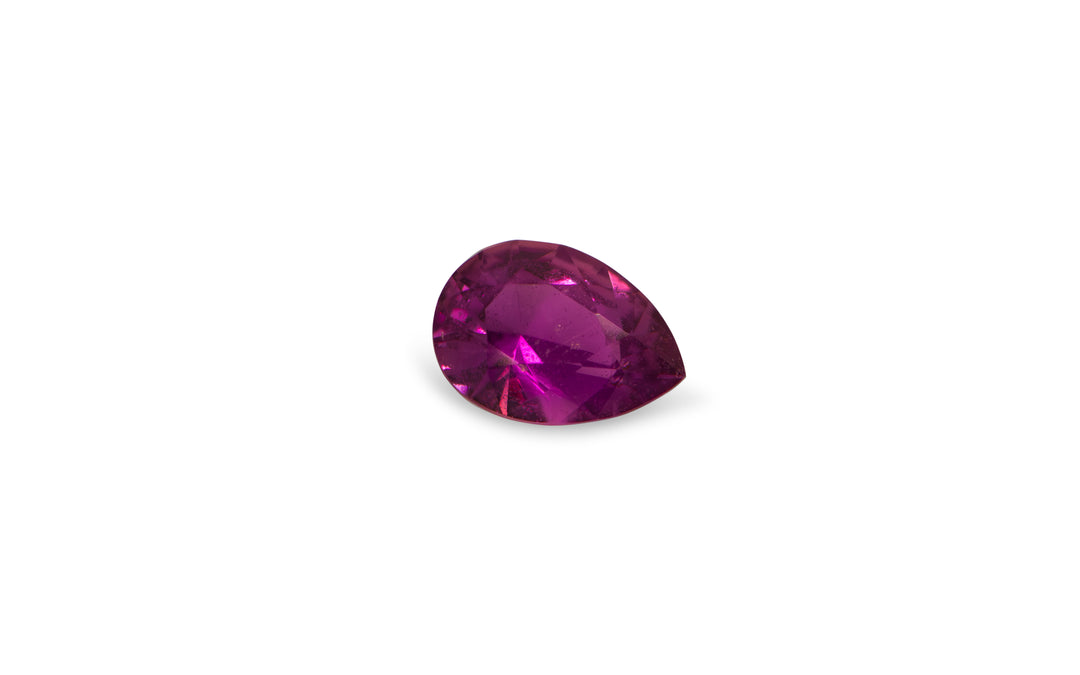 A pear cut cut pink Ceylon sapphire gemstone is displayed on a white background.