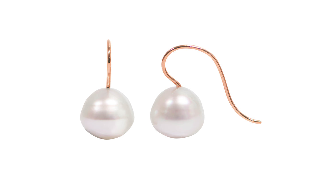 A pair of 18K rose gold circle pink white south sea pearl shepherd hook earrings is displayed on a white background.