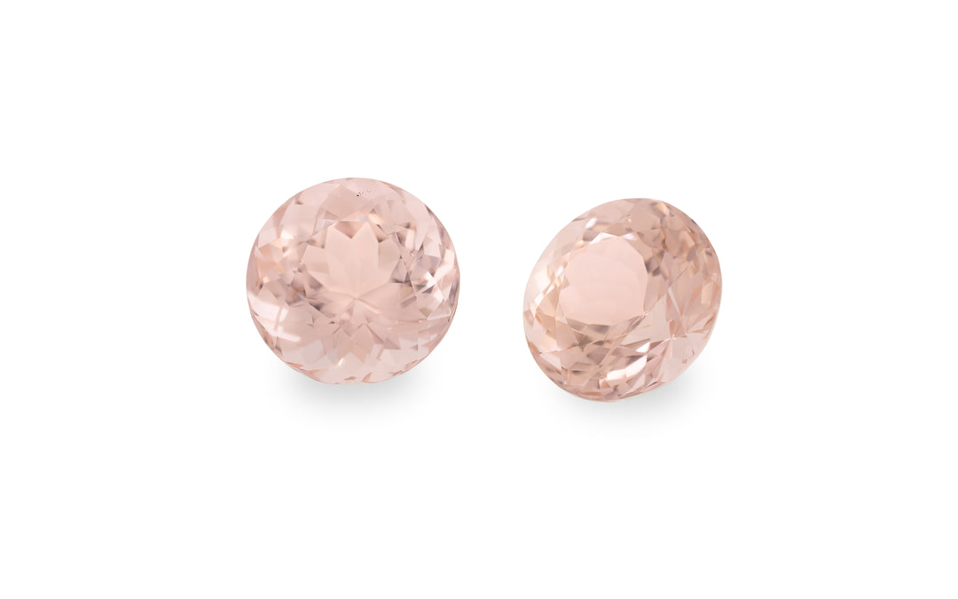 A pair of round cut peach morganite gemstone is displayed on a white background.