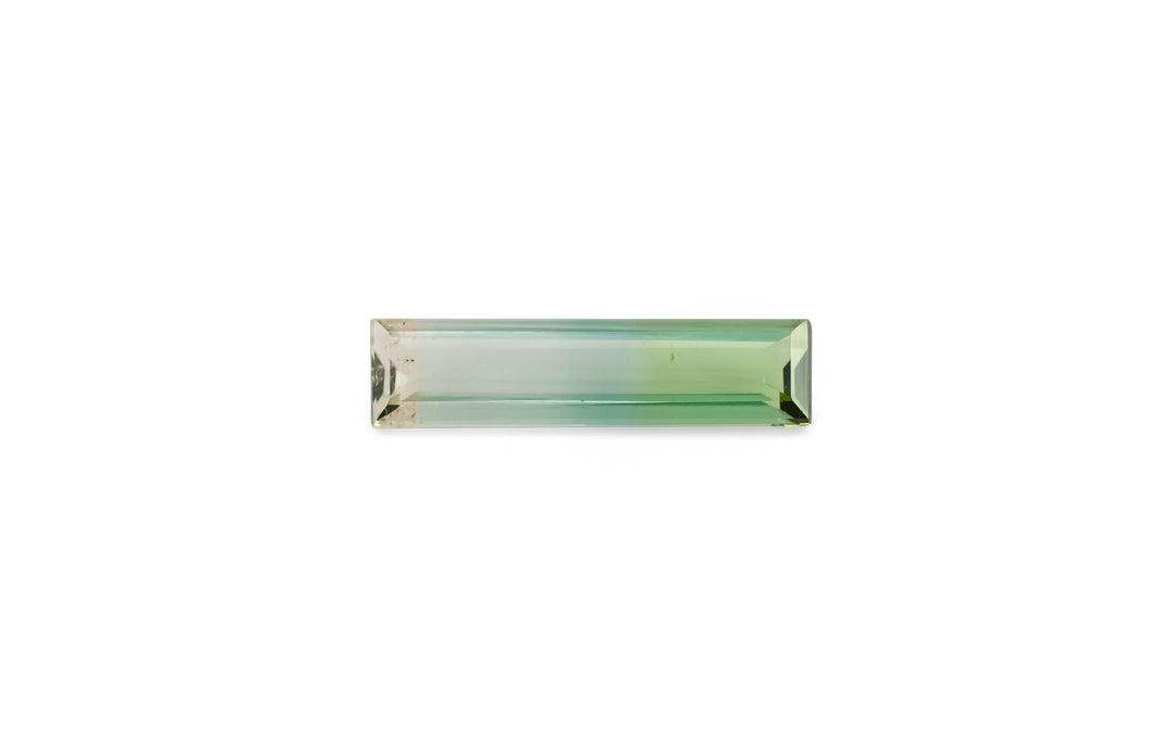A baguette cut, bi-colour, green and yellow tourmaline gemstone is displayed on a white background.