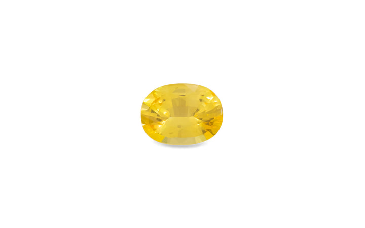 A cushion cut golden yellow Ceylon sapphire gemstone is displayed on a white background.