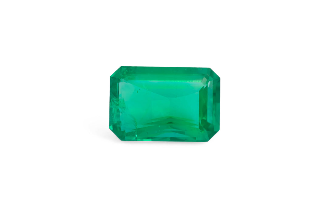 An emerald cut green Panjshir emerald gemstone is displayed on a white background.