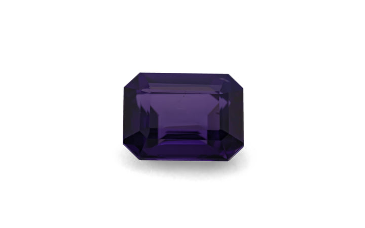 An emerald cut purple Sri Lankan spinel gemstone is displayed on a white background.