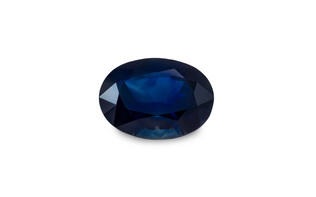  An oval cut blue Australian sapphire gemstone is displayed on a white background.