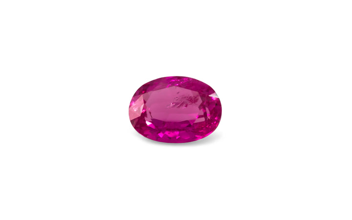 An oval cut vivid pink sapphire gemstone is displayed on a white background.