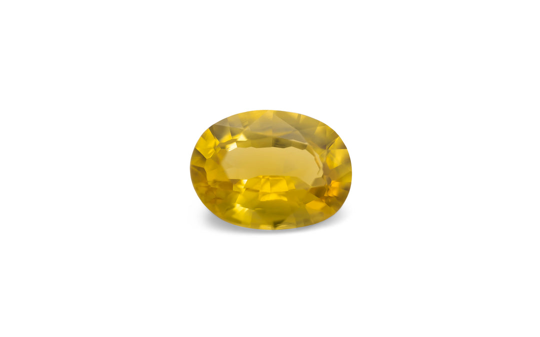 An oval cut golden yellow sapphire gemstone is displayed on a white background.