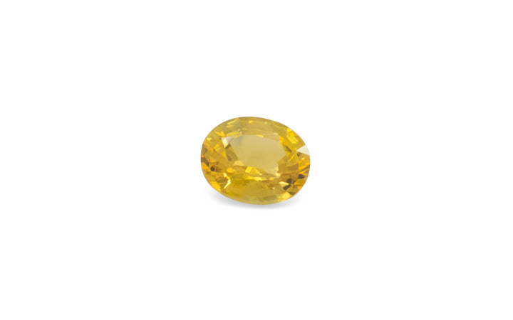 An oval cut golden yellow Ceylon sapphire is displayed on a white background.