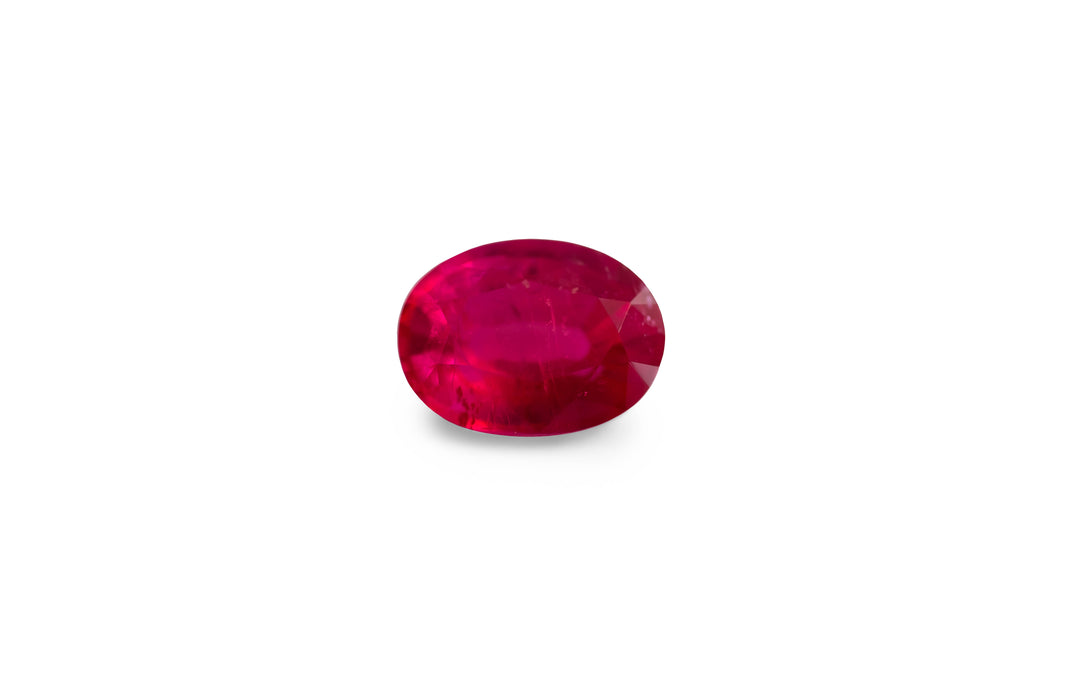An oval cut, red Burmese ruby gemstone is displayed on a white background.