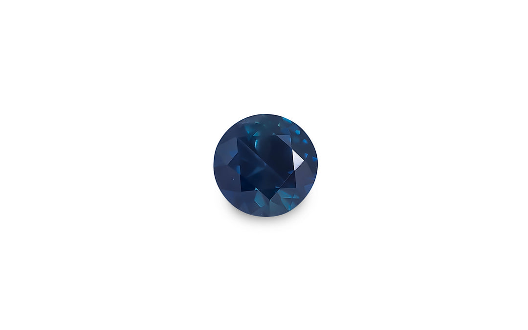 A round brilliant cut blue Australian sapphire gemstone is displayed on a white background.