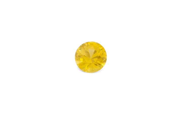 A round brilliant cut golden yellow Ceylon sapphire gemstone is displayed on a white background.